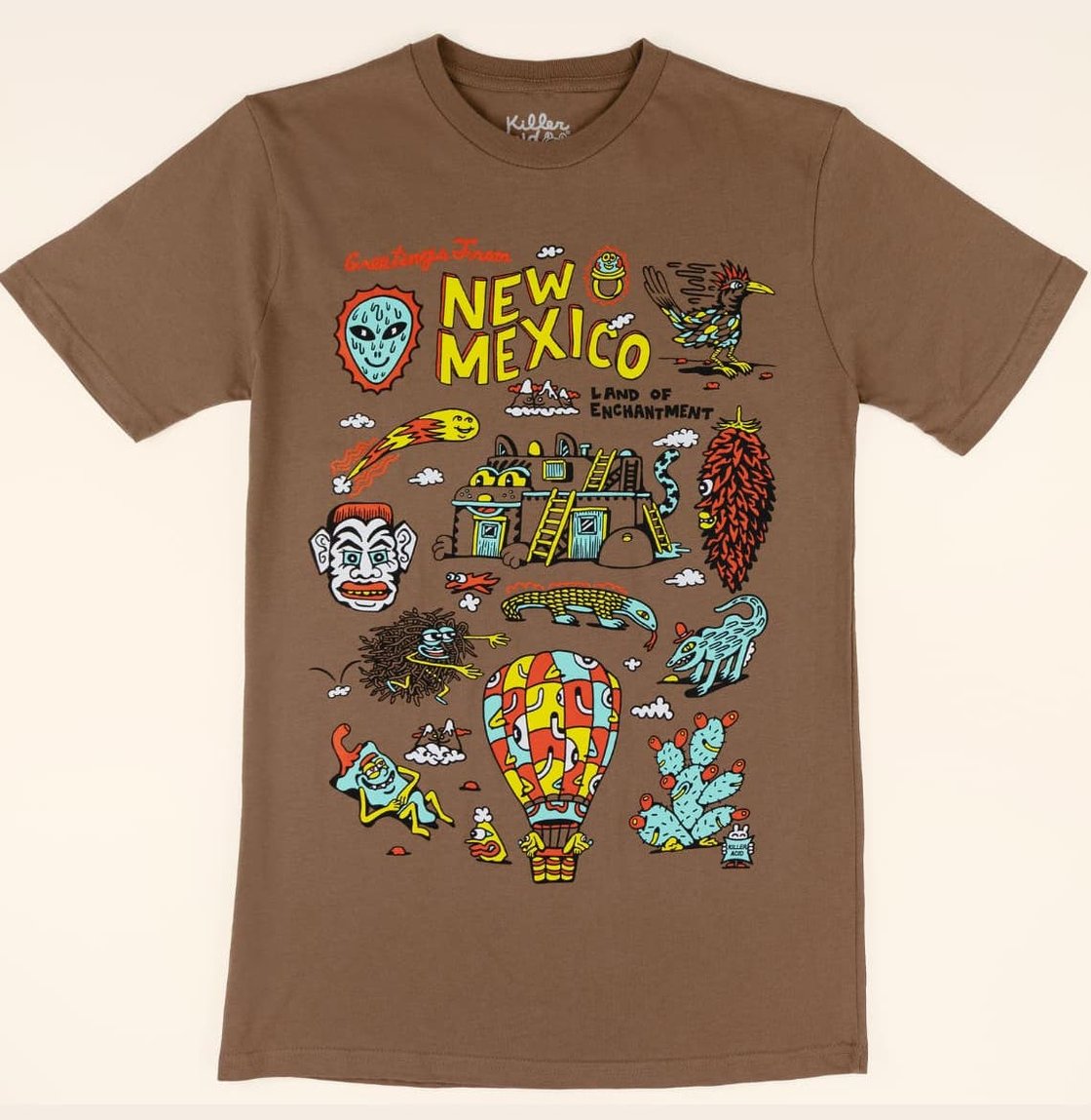 brown shirt with illustrations of New Mexico-based things like prickly pear cactus and Zozobra